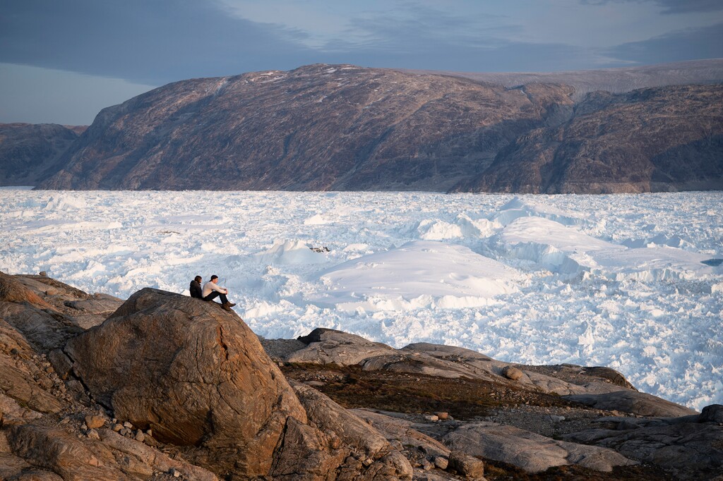 (Felipe Dana | AP) In this Aug. 16, 2019, file photo, NYU student researchers sit on top of a rock overlooking the Helheim glacier in Greenland. As warmer temperatures cause the ice to retreat the Arctic region is taking on new geopolitical and economic importance, and not just the United States hopes to stake a claim, with Russia, China and others all wanting in.
