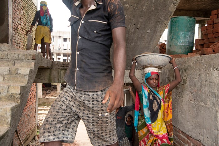 (Saumya Khandelwal | The New York Times) Rabita and her husband Ashok Kumar, left, carry sand up a stairwell, a task they repeat all day at the construction site where they both work and live in Lucknow, India, July 28, 2020. Rabita and her husband are Dalits, at the bottom of the Hindu caste ladder, working to pay off their debts.