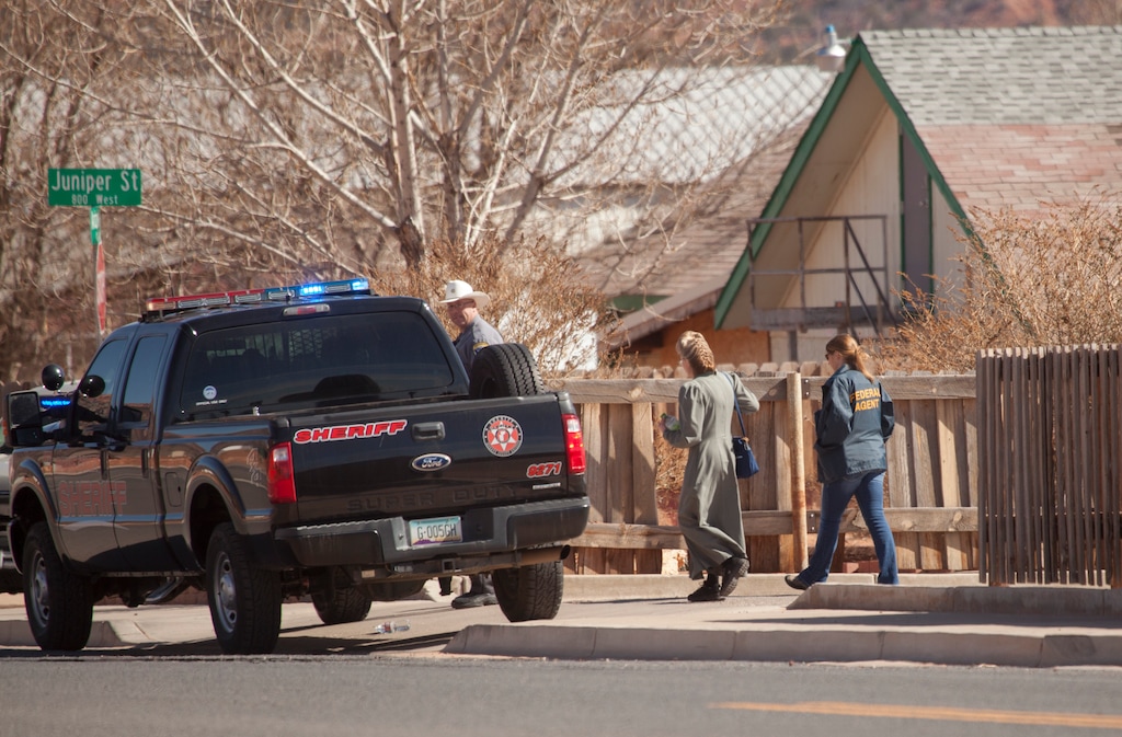 Law enforcement officers walk through Hildale, Utah on Tuesday, Feb. 23, 2016. Several top leaders from Warren Jeffs' polygamous sect were arrested Tuesday on federal accusations of food stamp fraud and money laundering marking one of the biggest crackdowns on the group in years. Lyle Jeffs, one of the 11 charged in the scheme, runs the day-to-day operations in the polygamous community. (Chris Caldwell/The Spectrum via AP)