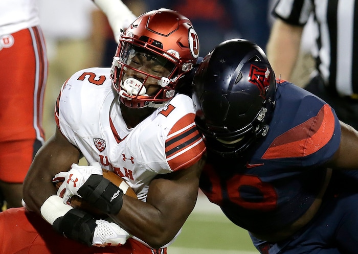 Utah running back Zack Moss (2) is tackled by Arizona defensive lineman Dereck Boles during the first half of an NCAA college football game, Friday, Sept. 22, 2017, in Tucson, Ariz. (AP Photo/Rick Scuteri)