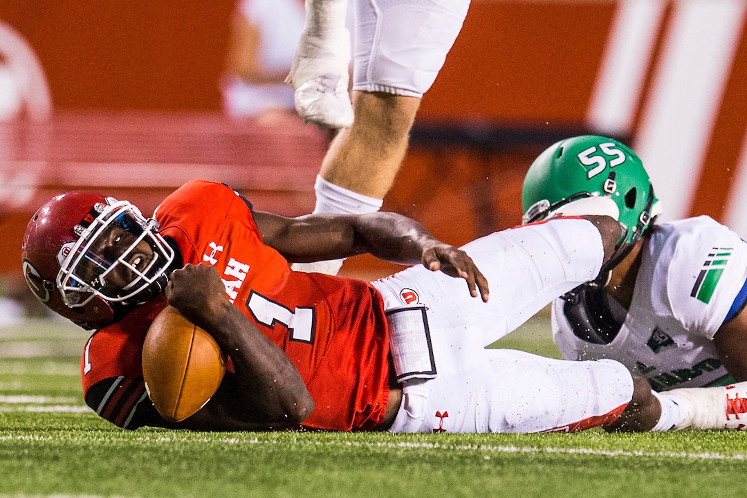 (Chris Detrick  |  The Salt Lake Tribune)  Utah Utes quarterback Tyler Huntley (1) is tackled by North Dakota Fighting Hawks defensive end Mason Bennett (55) during the game at Rice-Eccles Stadium Thursday, August 31, 2017. Utah Utes defeated North Dakota Fighting Hawks 37-16.