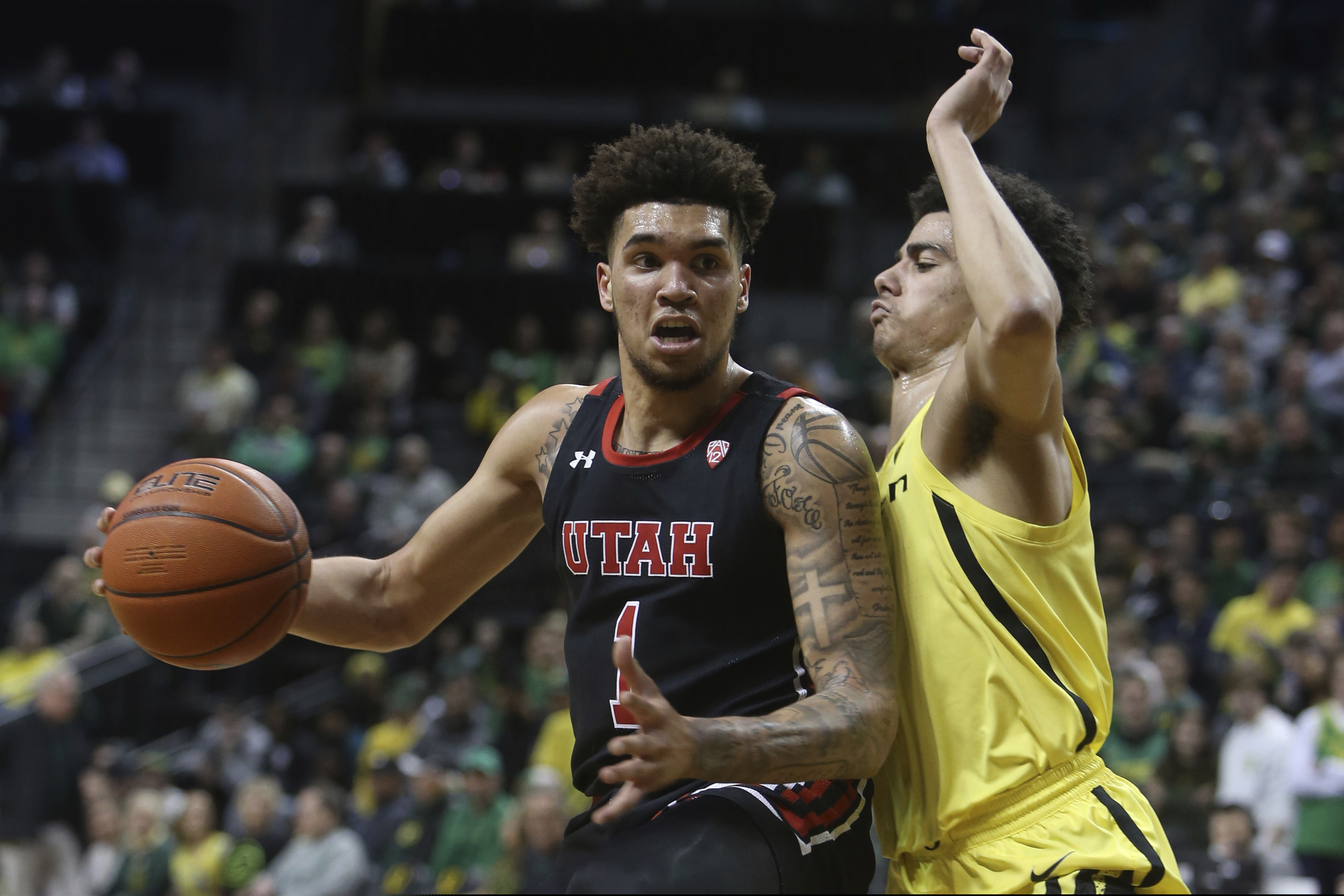 (Chris Pietsch | AP) Utah's Timmy Allen, left, maneuvers against Oregon's Will Richardson during the second half of an NCAA college basketball game in Eugene, Ore., Sunday, Feb. 16, 2020.