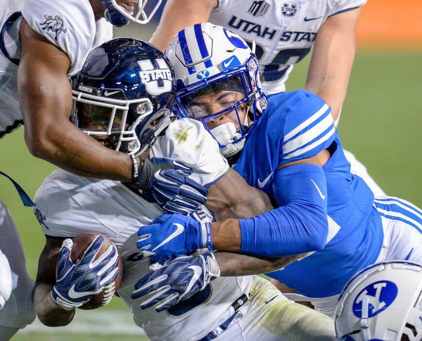 Leah Hogsten | The Salt Lake Tribune Brigham Young Cougars defensive back Chris Wilcox (32) brings down Utah State Aggies running back Darwin Thompson (5). Utah State University defeated BYU, 45-20, at Lavell Edwards Stadium in Provo, Friday, Oct. 5, 2018.