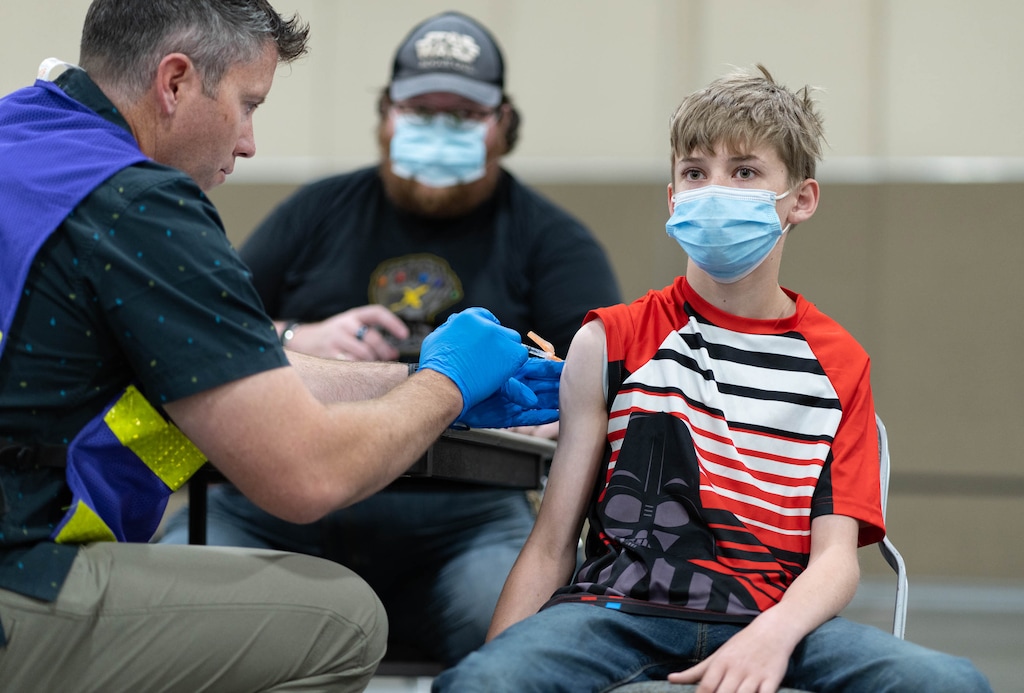 (Francisco Kjolseth | The Salt Lake Tribune) Hadley Brown, 13, of Magna accompanied by his father James, keeps his eyes away from the needle as EMT Sean Murphy administers the Pfizer vaccine, as 12-15 year olds get their vaccinations against COVID-19 at the Mountain America Expo Center in Sandy on Tuesday, May 18, 2021.