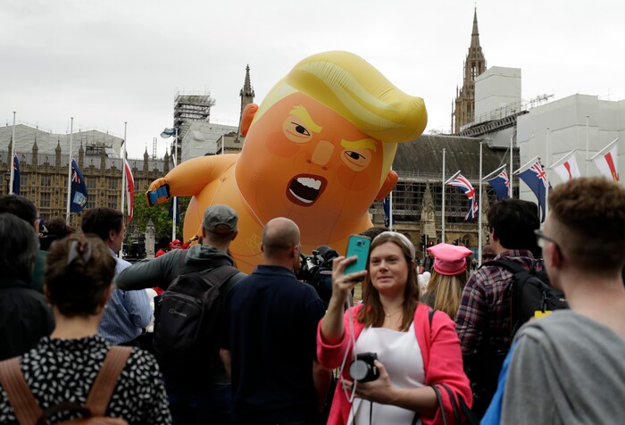 A woman takes a selfie as the 'Trump Baby' blimp is inflated in Parliament Square in central London as people start to gather to demonstrate against the state visit of President Donald Trump, Tuesday, June 4, 2019. Trump will turn from pageantry to policy Tuesday as he joins British Prime Minister Theresa May for a day of talks likely to highlight fresh uncertainty in the allies' storied relationship. (AP Photo/Matt Dunham)