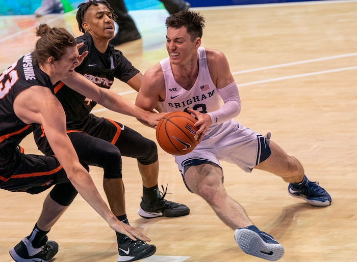 (Rick Egan | The Salt Lake Tribune) Brigham Young Cougars guard Brandon Averette (4) dribbles the ball up the middle, Pacific Tigers center James Hampshire (33) and Daniss Jenkins (4) defend, in basketball action at the Marriott Center in Provo, on Saturday, Jan. 30, 2021.