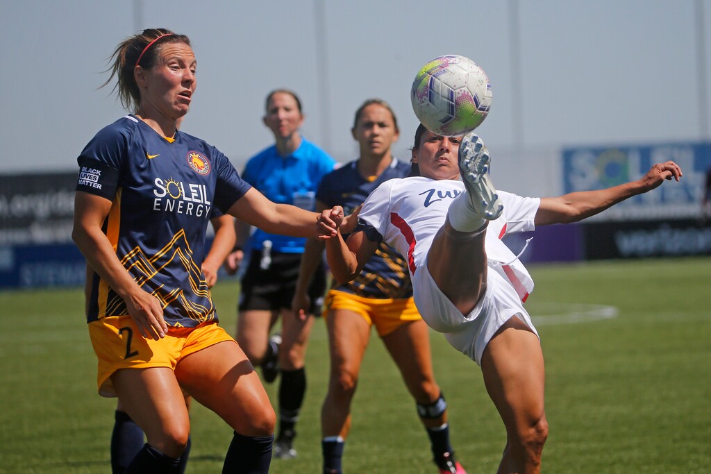 OL Reign midfielder Shirley Cruz, right, kicks the ball as Utah Royals FC defender Rachel Corsie (2) looks on during the first half of an NWSL Challenge Cup soccer match at Zions Bank Stadium Wednesday, July 8, 2020, in Herriman, Utah. (AP Photo/Rick Bowmer)