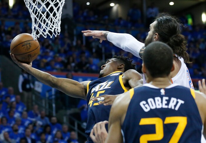 Utah Jazz guard Donovan Mitchell (45) shoots as Oklahoma City Thunder center Steven Adams, right, defends from behind in the second half of Game 1 of an NBA basketball first-round playoff series in Oklahoma City, Sunday, April 15, 2018. (AP Photo/Sue Ogrocki)