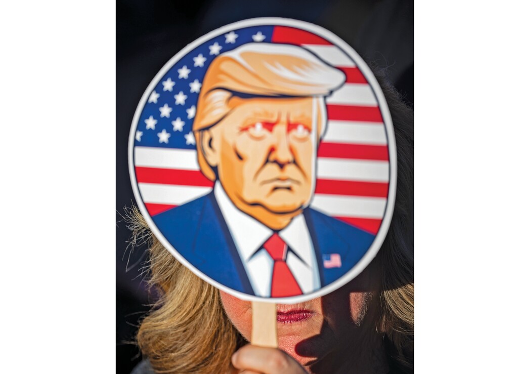 FILE — A woman holds up a fan depicting then-former President Donald Trump an an election campaign rally in Latrobe, Pa., on Oct. 19, 2024.  (Damon Winter/The New York Times)