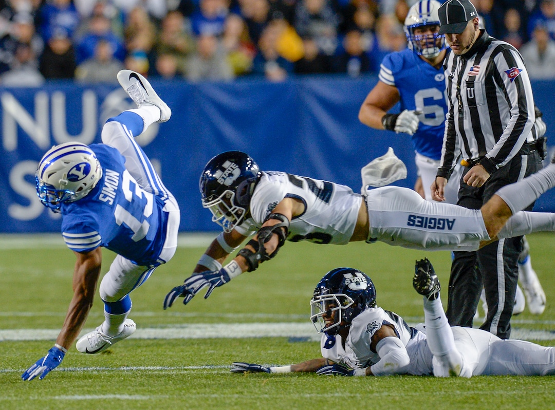 Leah Hogsten  |  The Salt Lake Tribune  Brigham Young Cougars wide receiver Micah Simon (13) is brought down by Utah State Aggies safety Gaje Ferguson (23) and Utah State Aggies defensive end Dalton Baker (24) as BYU hosts Utah State University at Lavell Edwards Stadium in Provo, Friday, Oct. 5, 2018.