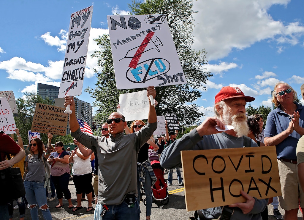FILE - In this Aug. 30, 2020 file photo, Sal Lando, left, of Sterling, holds up signs during a protest against mandatory flu vaccinations, outside the Massachusetts State House, in Boston. Years before this year's anti-mask and reopening demonstrations, vaccine opponents were working on reinventing their image around a rallying cry of civil liberties and medical freedom. Now, boosted by the pandemic and the political climate, their rebranding is appealing to a different subset of society invested in civil liberties — and, some health officials say, undercutting public health efforts during a critical moment for vaccines. (Nancy Lane/Boston Herald via AP, File)