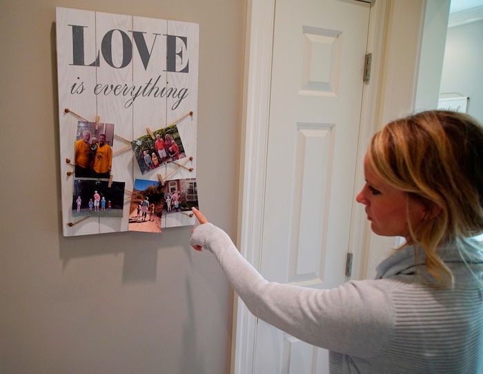 In this Wednesday, March 27, 2019, photo, Kacey Ruegsegger Johnson looks at photos of her family at her home in Cary, N.C. Ruegsegger Johnson survived a shotgun blast during the 1999 shootings at Colorado's Columbine High School that left 12 students, one teacher, and both gunmen dead. (AP Photo/Allen G. Breed)