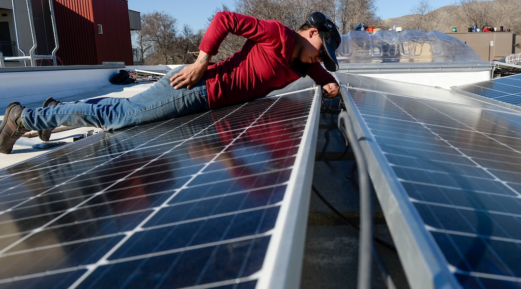 (Leah Hogsten  |  The Salt Lake Tribune) Jenny Melgoza, a Creative Energies commercial lead, installs photovoltaic panels on the roof of the Boys and Girls Club in Salt Lake City, March 5, 2020.