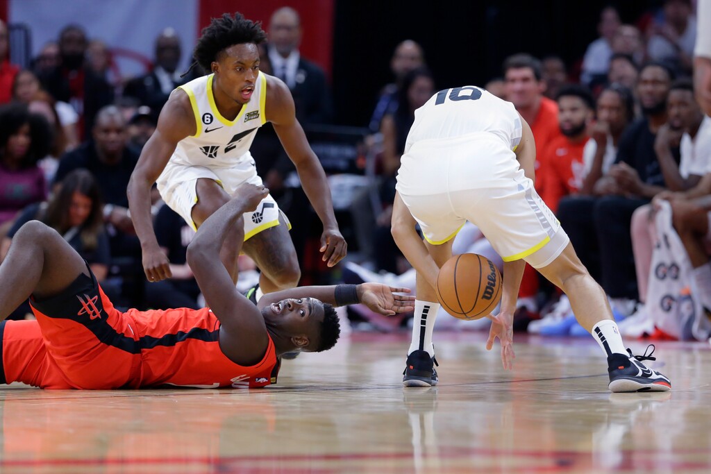 (Michael Wyke  |  The Associated Press) Houston Rockets forward Usman Garuba, bottom, reaches for the ball as it goes through the legs of Utah Jazz forward Simone Fontecchio, right, as Jazz guard Collin Sexton, top left, looks on during the second half of an NBA basketball game Monday, Oct. 24, 2022, in Houston.