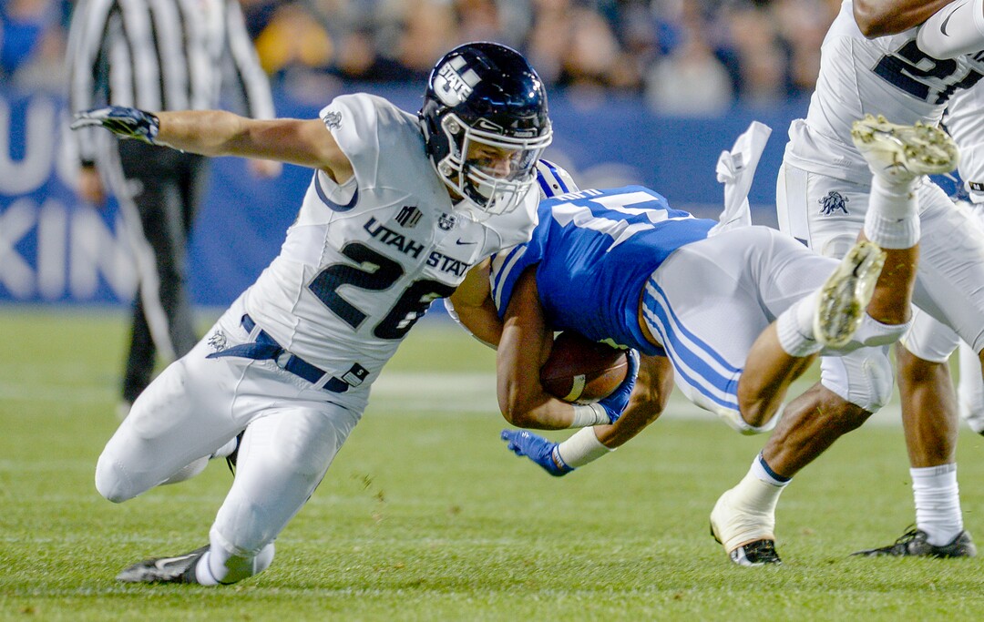 Leah Hogsten  |  The Salt Lake Tribune  Brigham Young Cougars wide receiver Aleva Hifo (15) is brought down by Utah State Aggies safety Chase Nelson (26)as BYU hosts Utah State University at Lavell Edwards Stadium in Provo, Friday, Oct. 5, 2018.