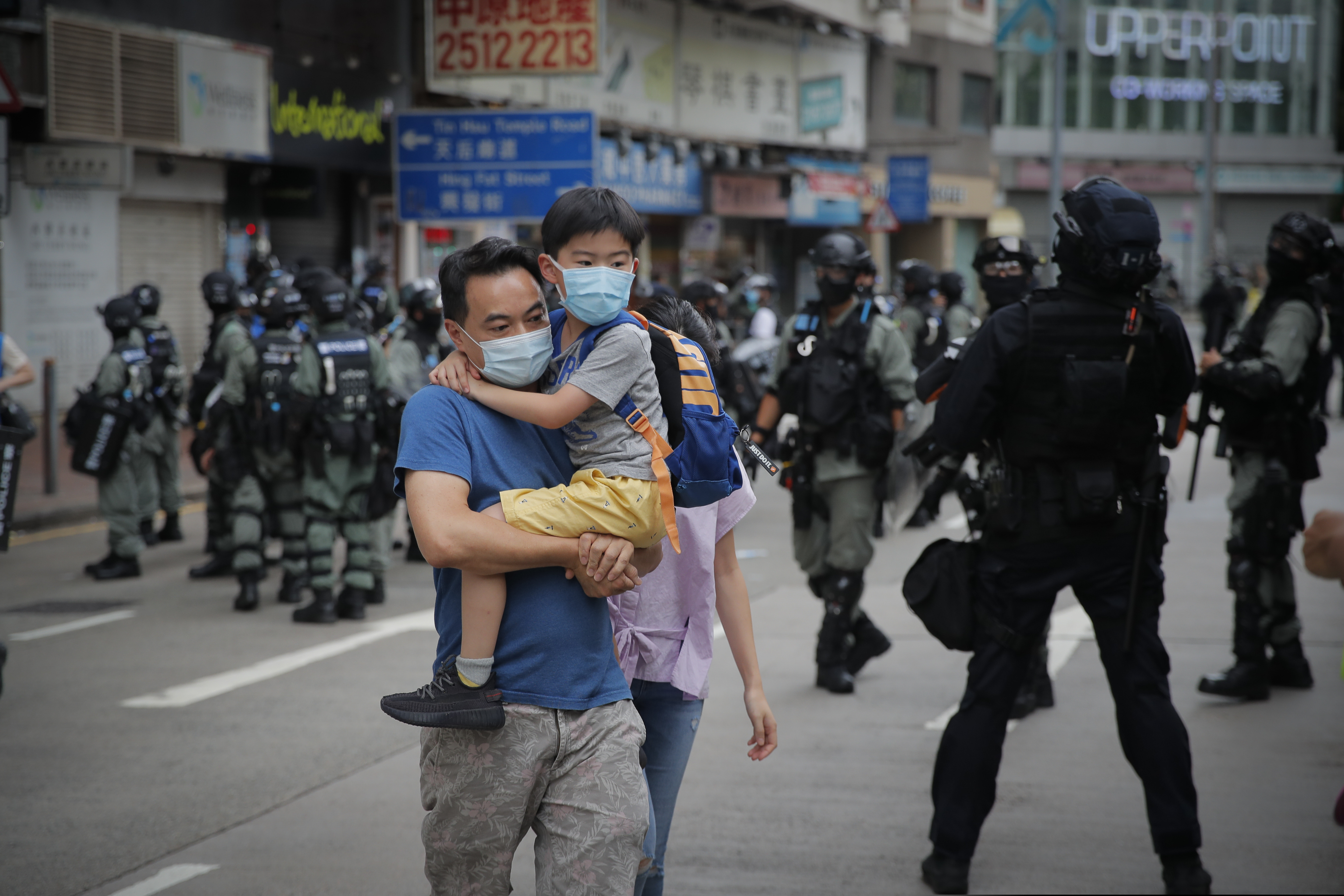 (Kin Cheung | AP file photo) A man carries his son across a road while riot police push back protesters on the anniversary of Hong Kong's handover to China from Britain in Hong Kong on July. 1, 2020. Hong Kong marked the 23rd anniversary of its handover to China in 1997, and just one day after China enacted a national security law that cracks down on protests in the territory.