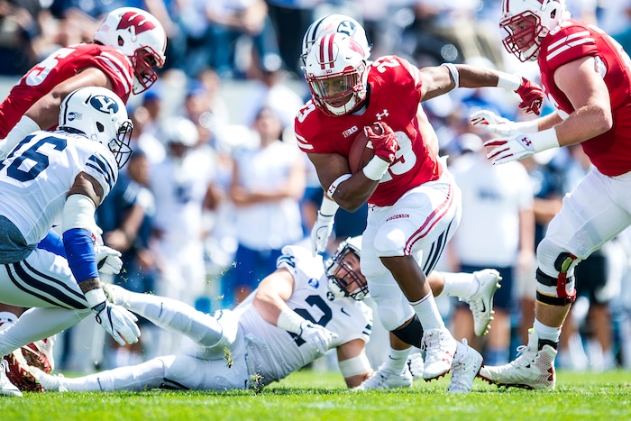 (Chris Detrick  |  The Salt Lake Tribune)   Wisconsin Badgers running back Jonathan Taylor (23) runs the ball past Brigham Young Cougars defensive lineman Sione Takitaki (16) and Brigham Young Cougars linebacker Matt Hadley (2) during the game at LaVell Edwards Stadium Saturday Saturday, September 16, 2017. Wisconsin Badgers are leading Brigham Young Cougars 24-6 at halftime.