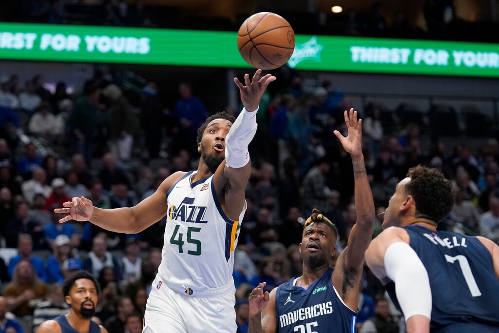 Utah Jazz guard Donovan Mitchell (45) goes up to shoot in front of Dallas Mavericks' Reggie Bullock, center, and Dwight Powell (7) in the first half of an NBA basketball game in Dallas, Monday, March, 7, 2022. (AP Photo/Tony Gutierrez)