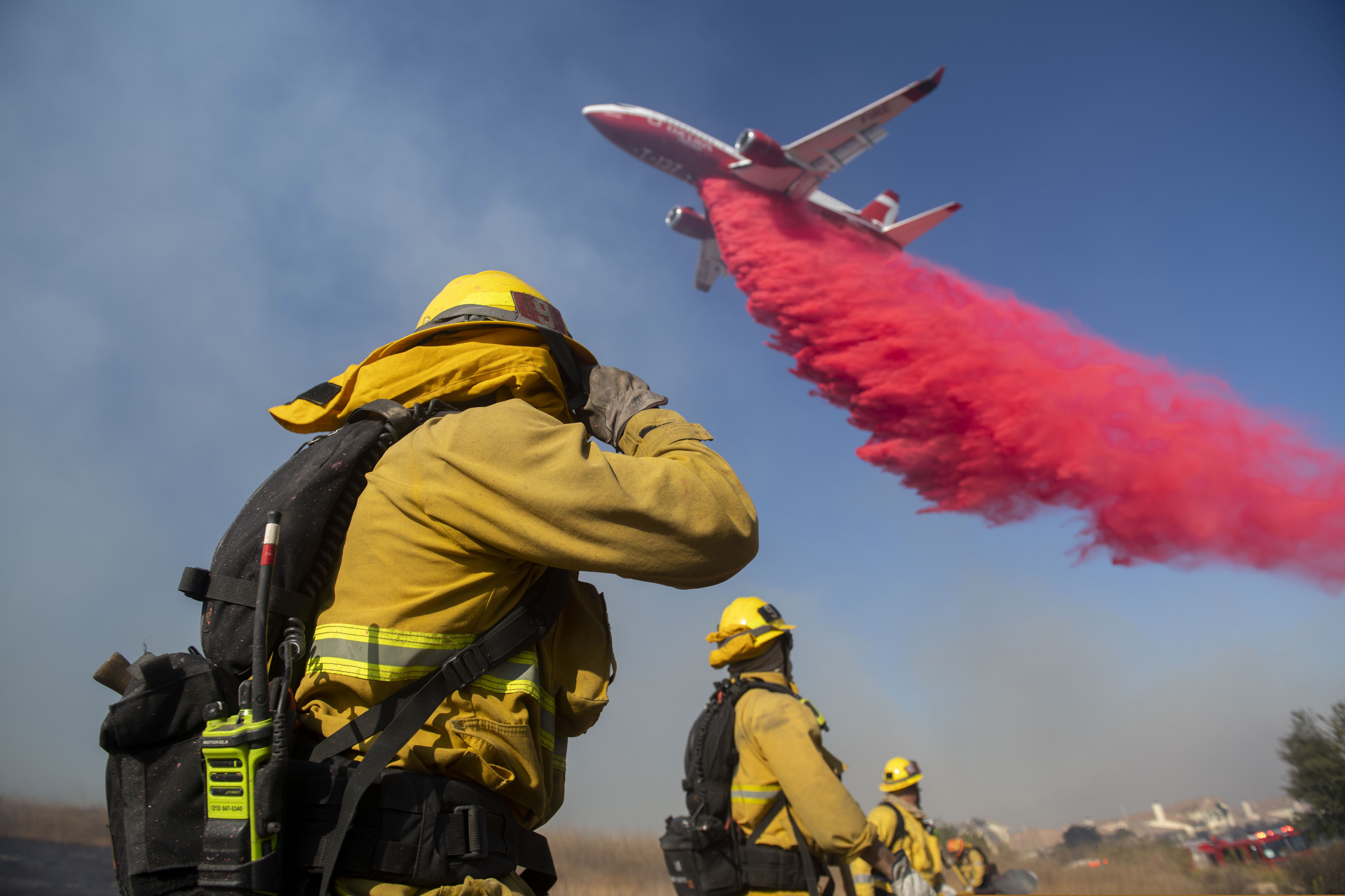 (Christian Monterrosa | AP) Firefighters brace themselves for incoming fire retardant during the Easy Fire, Wednesday, Oct. 30, 2019, in Simi Valley, Calif. Fire officials say they're investigating the cause of the fire.