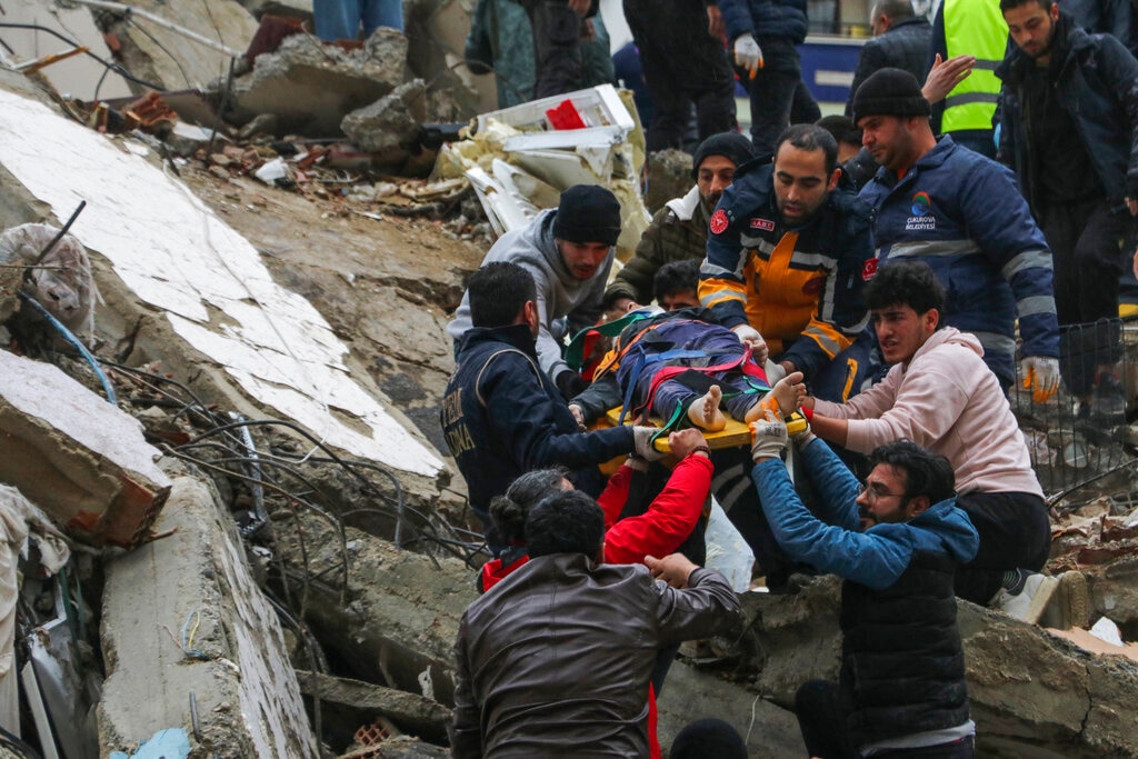 (IHA agency via AP) People and emergency teams rescue a person on a stretcher from a collapsed building in Adana, Turkey, Monday, Feb. 6, 2023. A powerful quake has knocked down multiple buildings in southeast Turkey and Syria and many casualties are feared.
