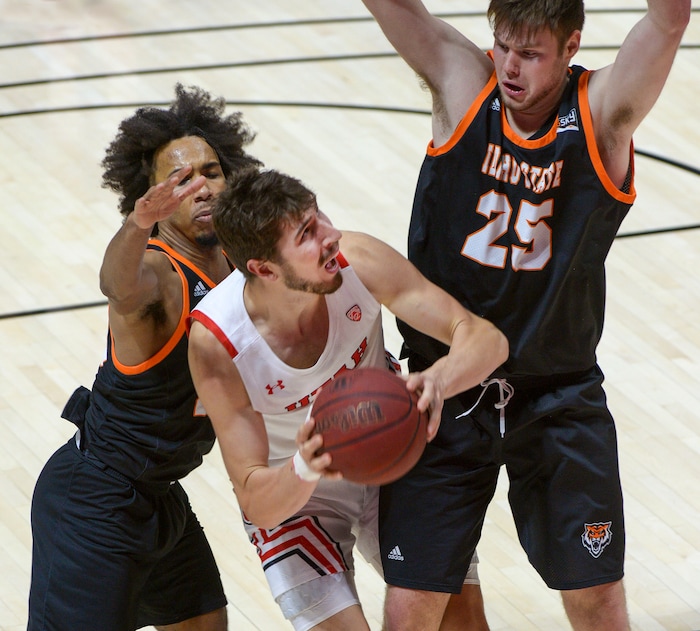 (Leah Hogsten  |  The Salt Lake Tribune) Utah Utes forward Riley Battin (21) drives to the net between Idaho State Bengals guard Robert Ford III (20) and Idaho State Bengals center Brayden Parker (25) during their NCAA basketball matchup Tuesday, Dec. 8, 2020 at the Jon M. Huntsman Center. Utes defeated Idaho State 75-59.