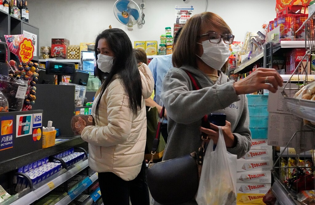 (AP Photo/Vincent Yu) People wear protective face masks as they make purchases from a convenience store in Hong Kong, Monday, Feb, 3, 2020. Hong Kong leader Carrie Lam in a Monday press conference says the city will shut almost all land and sea border control points to the mainland from midnight to stem the spread of the novel coronavirus from China.