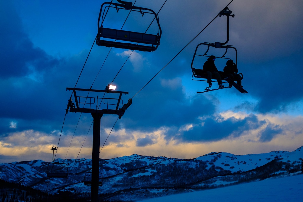 (Trent Nelson  |  The Salt Lake Tribune) Snowboarders on a lift as night sets in at Brighton on Monday, Feb. 24, 2020. Brighton has added snowmaking and lights to its Snake Creek run and will be opening it up for night skiing this season.