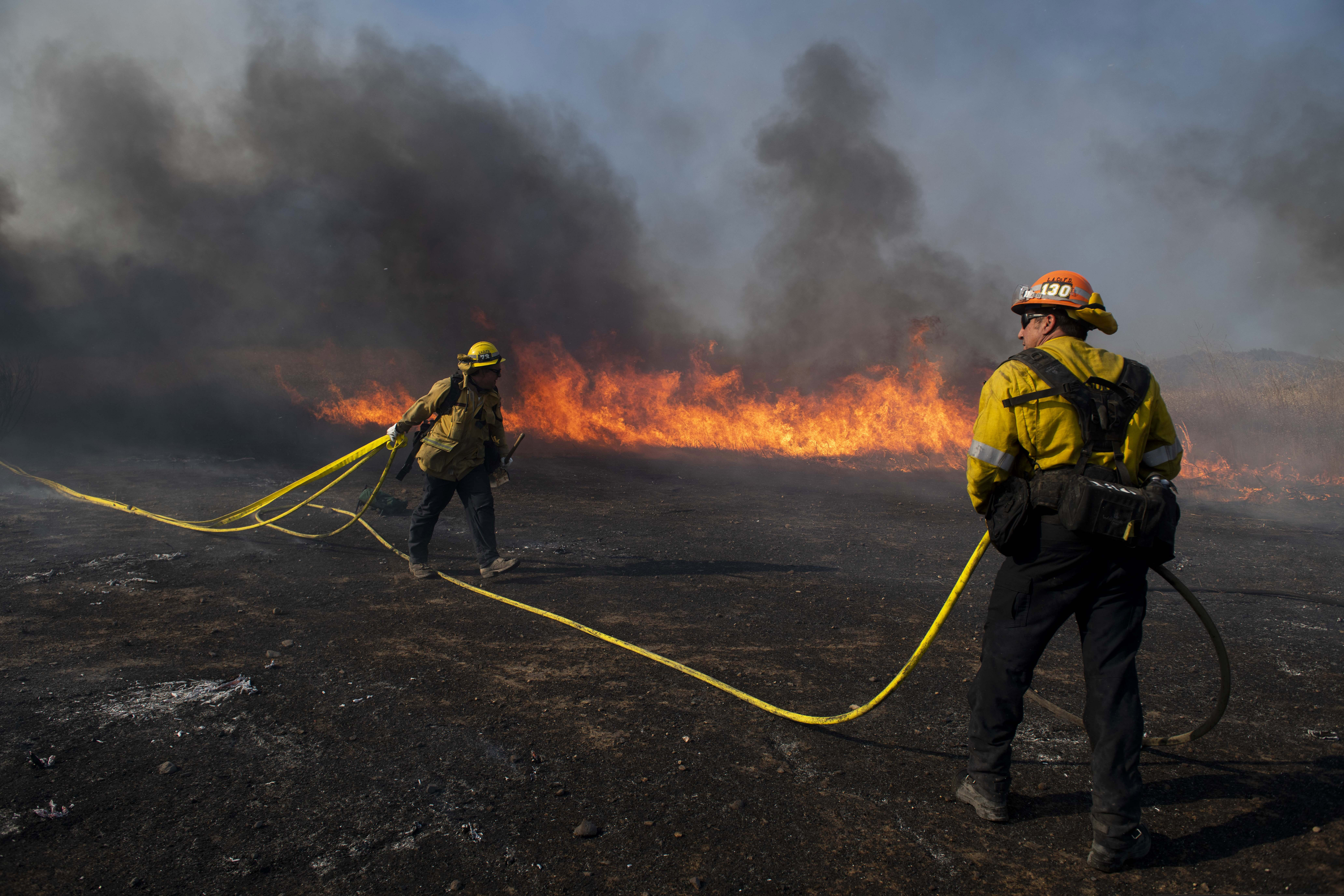 (Christian Monterrosa | AP) Firefighters work to prevent flames from reaching nearby homes while battling the Easy Fire, Wednesday, Oct. 30, 2019, in Simi Valley, Calif.  It has chewed through brush and trees near suburbs, horse ranches and the Ronald Reagan Presidential Library.