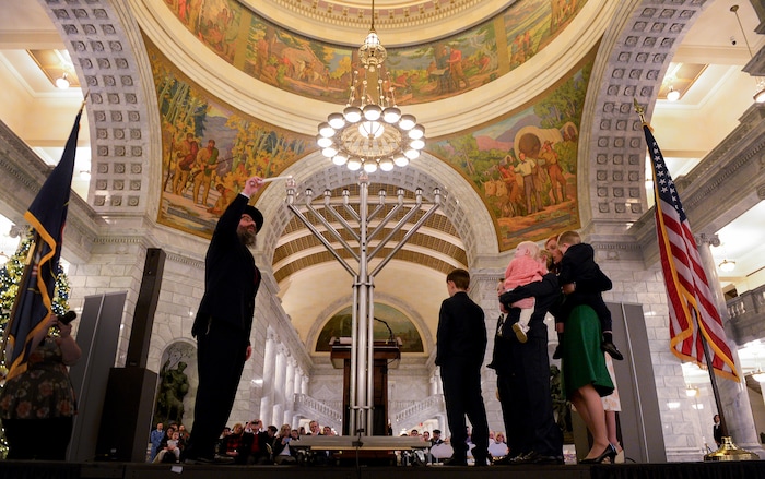 Leah Hogsten  |  The Salt Lake Tribune  l-r Rabbi Benny Zippel with Chabad Lubavitch of Utah is joined by Jennie Taylor and her seven children as he lights the Menorah during the 12th annual Hanukkah celebration at the Utah Capitol on Dec. 2, 2018. The event was also dedicated as 'A Salute to a Hero', in tribute to the late Maj. Brent Taylor of North Ogden, as the Menorah was kindled by his wife, Jennie Taylor.