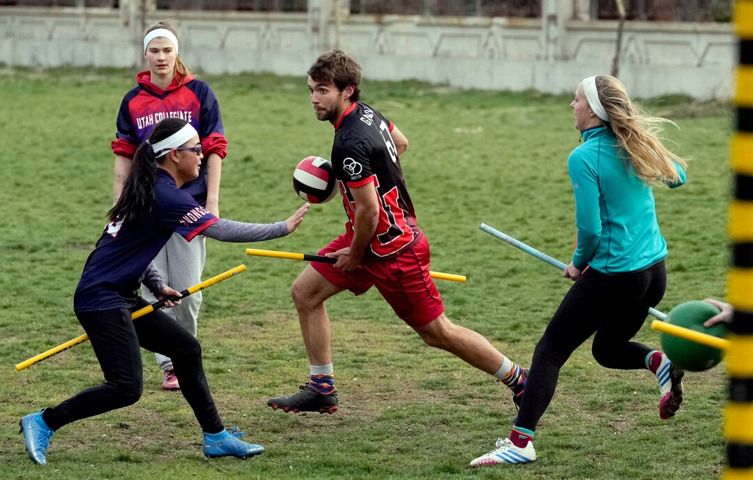 (Francisco Kjolseth | The Salt Lake Tribune) Hannah Winslow, left, and Katie Ely try to put defensive pressure on Porter Birchum as they practice Quidditch at Reservoir Park in Salt Lake City on Wednesday, April 13, 2022. Based off the Harry Potter books, Quidditch requires each player to keep a broom stick between their legs at all times as three chasers, two beaters, a keeper and a seeker work to score points by getting the quaffle (a volleyball) through a hoop. 