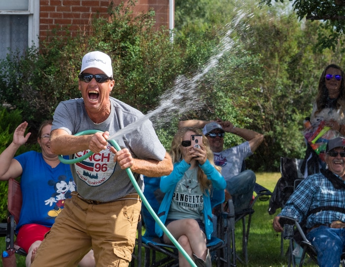 (Rick Egan | The Salt Lake Tribune) 
A parade watcher grabs the hose as he battles the water balloons from the Panguitch High Wrestling team during the Pioneer Day Parade in Panguitch, Saturday, July 23, 2022.
