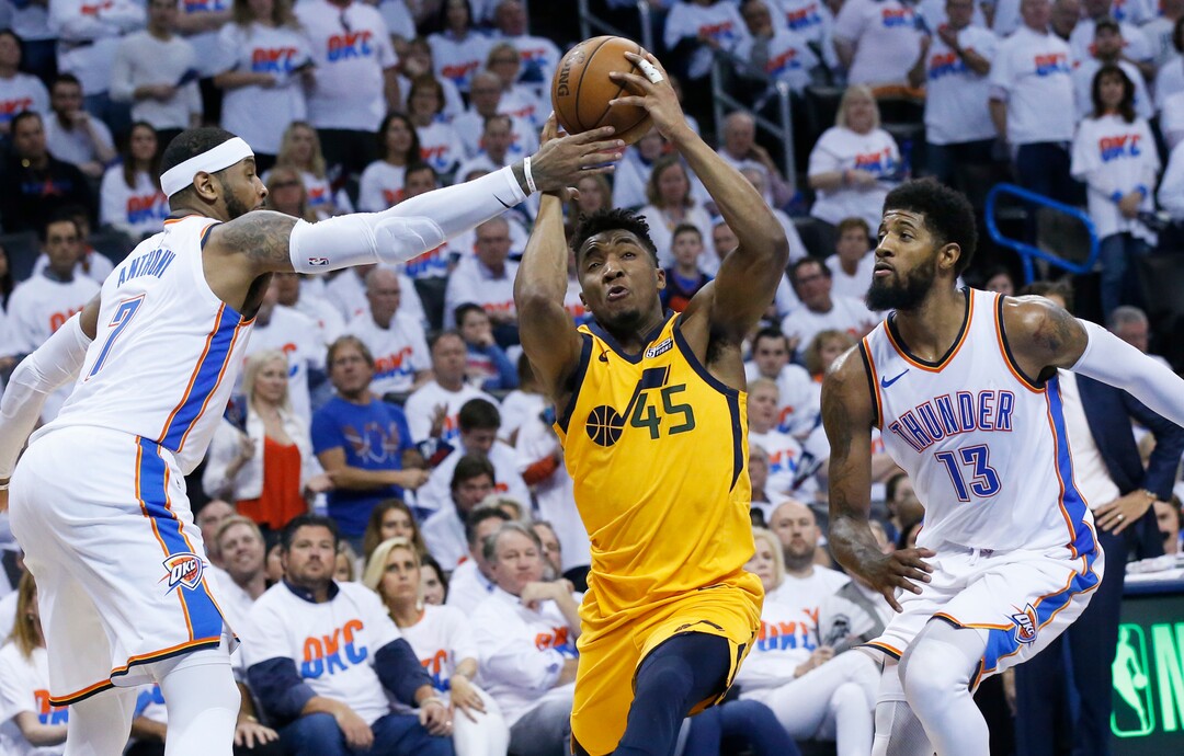Oklahoma City Thunder forward Carmelo Anthony (7) reaches in to knock the ball away from Utah Jazz guard Donovan Mitchell (45) as Mitchell drives between Anthony and forward Paul George (13) in the second half of Game 2 of an NBA basketball first-round playoff series in Oklahoma City, Wednesday, April 18, 2018. (AP Photo/Sue Ogrocki)