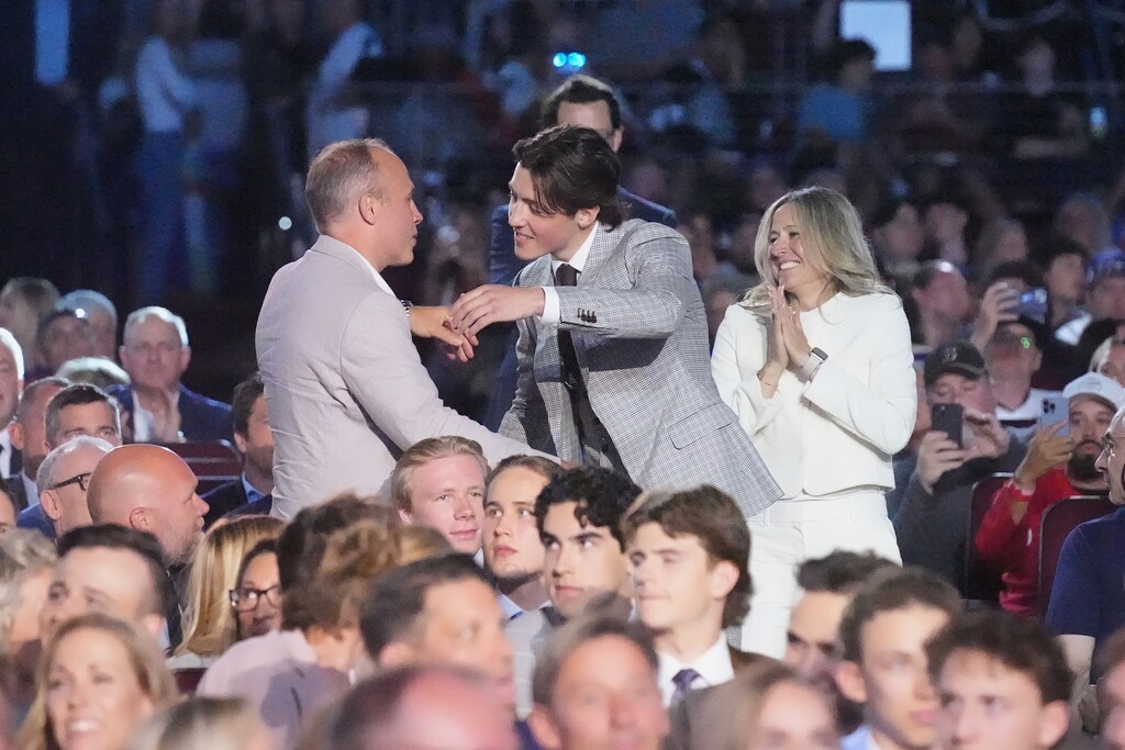 Caleb Desnoyers, middle, is congratulated after being drafted by the Utah Mammoth during the NHL hockey draft Friday, June 27, 2025, in Los Angeles. (AP Photo/Damian Dovarganes)