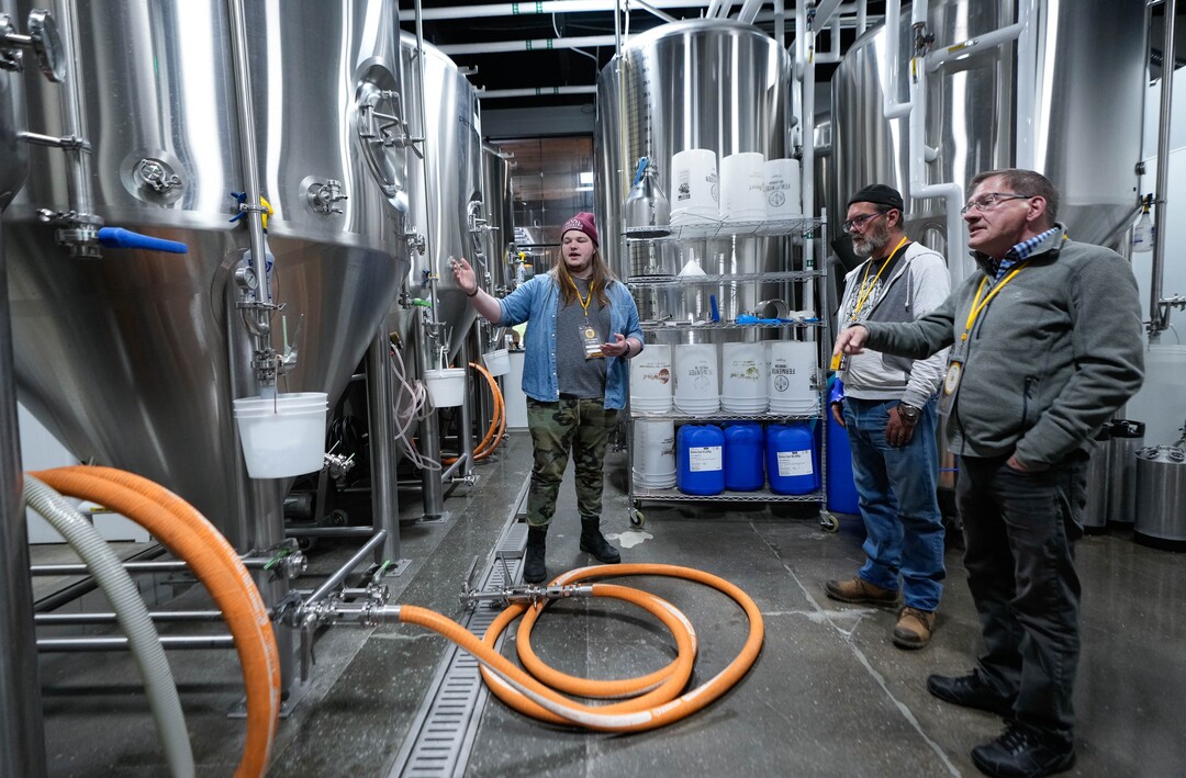 (Francisco Kjolseth | The Salt Lake Tribune) City Brew Tours in Salt Lake Liam Bice, center, gives Dane Hofmann  and Charley Ellis a behind the scenes look at the process at Level Crossing Brewery on Saturday, April 30, 2022. The new educational beer tour takes folks around to local breweries to see the back end brewing process, sample beers and pair them with food. 