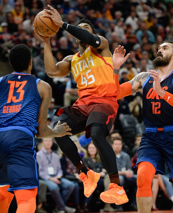 (Francisco Kjolseth  |  The Salt Lake Tribune)   Utah Jazz guard Donovan Mitchell (45) keeps his eye on the basket as he battles Oklahoma City Thunder forward Paul George (13) and Oklahoma City Thunder center Steven Adams (12) in the NBA game at Vivint Smart Home Arena Sat., Dec. 22, 2018, in Salt Lake City.