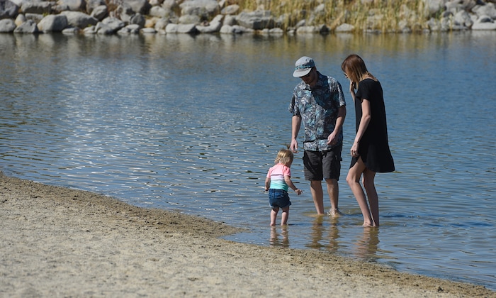 (Francisco Kjolseth  |  The Salt Lake Tribune)  Brian and McKenzie McDonald wander into Black Ridge Reservoir in Herriman with their daughter Penelope, 14-months, before being warned about the small warning signs posted at popular recreation site on Tuesday, Aug. 28, 2018, where an outbreak of algae-related toxin cyanobacteria was detected in the water.