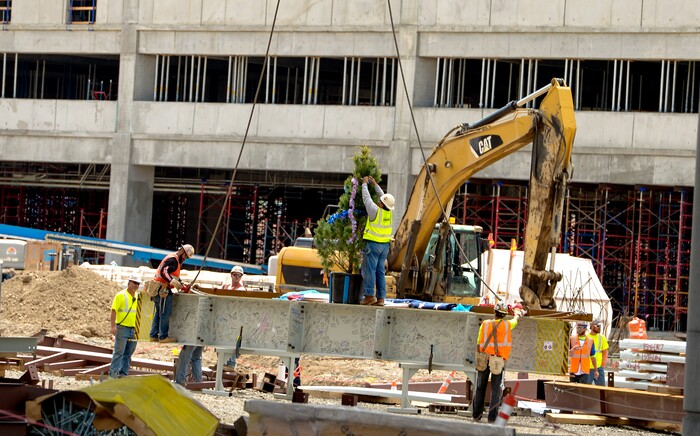(Leah Hogsten  |  The Salt Lake Tribune) Iron Workers Local Union 27 rig the last steel beam with a tinsel decorated tree during a "topping out" ceremony at the new Salt Lake City International terminal building, Wednesday, May 23, 2018. Such ceremonies can be traced to Scandinavian rites to place a tree atop a new building to appease the tree-dwelling spirits displaced during Construction.