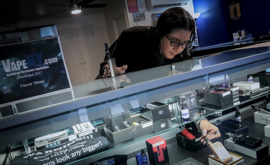 (Bebeto Matthews | AP file photo) Spike Babaian, owner of several Vape New York stores, works in her East Harlem store in New York on Oct. 8, 2019. Sales at small businesses that sell vaping products have plunged since August, when reports of vaping-related illnesses and deaths began. “We can never undo the government going on the news and saying it’s not safe to vape. The damage has been done,” says Babaian, who has been in business for eight years.