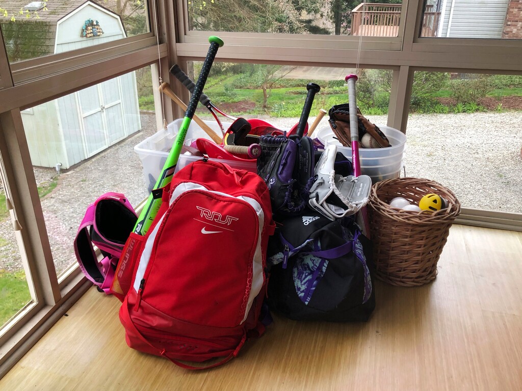 (Will Graves | AP) Baseball and softball bags for Colin and Catherine Graves lie untouched in Monroeville, Pa., April 14, 2020. Doctors, scientists and sports leaders are outlining the path back to playing fields for children in grassroots sports -- an exercise that could inform major organizations on how to get their industries up and running as well in the midst of the COVID-19 pandemic.