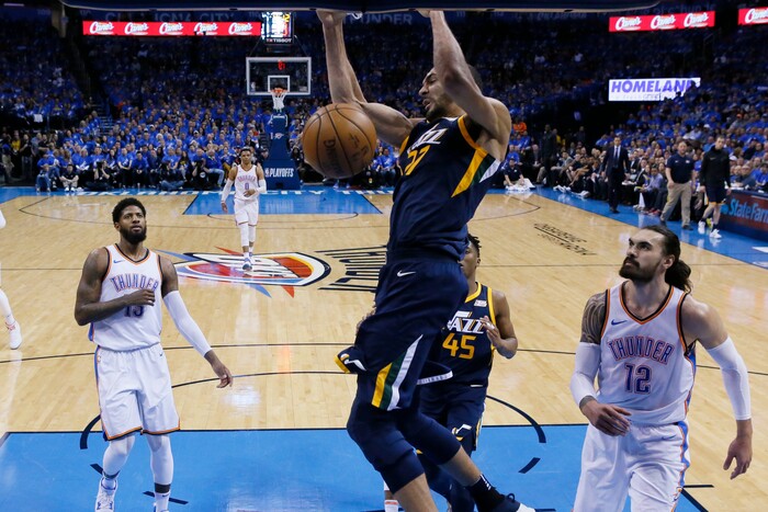 Utah Jazz center Rudy Gobert (27) dunks between Oklahoma City Thunder forward Paul George (13) and center Steven Adams (12) in the first half of Game 1 of an NBA basketball first-round playoff series in Oklahoma City, Sunday, April 15, 2018. (AP Photo/Sue Ogrocki)