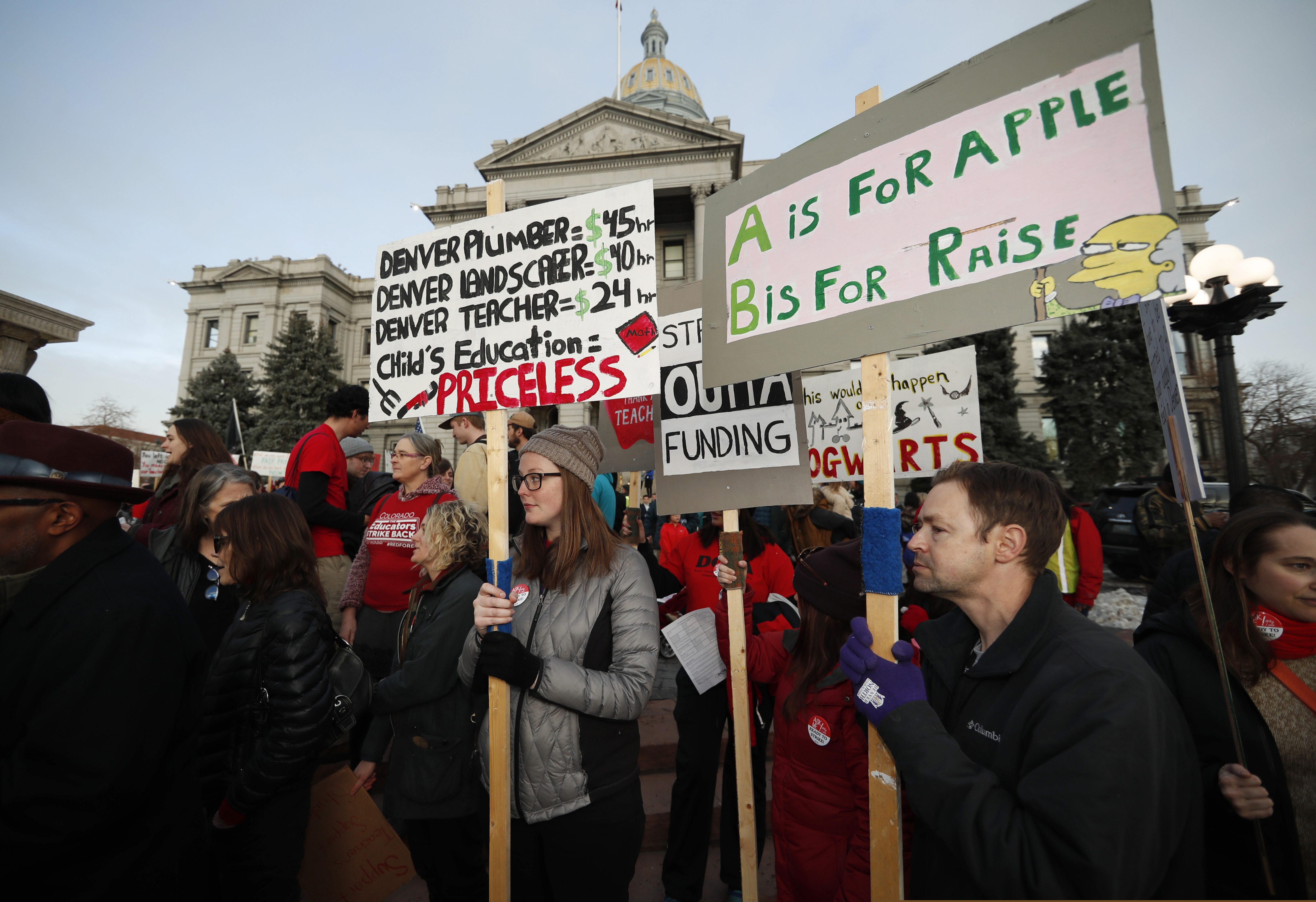 FILE - In this Wednesday, Jan. 30, 2019, file photo, teachers from the Denver Public Schools carry placards as they wait to march after a rally in support of a strike outside the State Capitol in Denver. Denver teachers are planning to strike Monday, Feb. 11, 2019 after failed negotiations with the school district over base pay. (AP Photo/David Zalubowski, File)