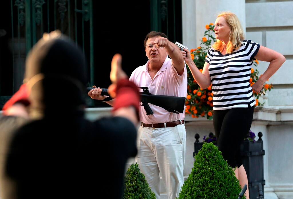 (Laurie Skrivan | St. Louis Post-Dispatch via AP)
In this June 28 photo, armed homeowners Mark and Patricia McCloskey, standing in front their house along Portland Place confront protesters marching to St. Louis Mayor Lyda Krewson's house in the Central West End of St. Louis. An affidavit in a court case shows that the white St. Louis couple who stood outside their mansion with guns during a protest have pulled a gun before. Mark McCloskey says in the affidavit that they pointed a gun at a neighbor once as a warning to stay off their property. They claim they own a small piece of land, while trustees of their private street say they own it.