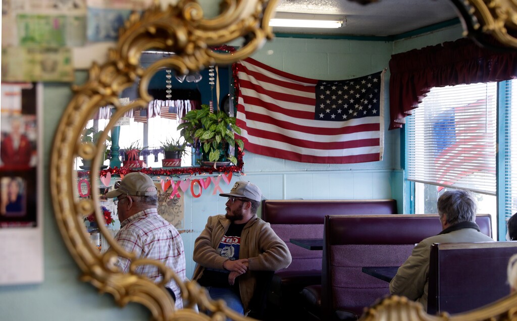 (Eric Gay | The Associated Press) In this Wednesday, Jan. 23, 2019, photo, Gene Henderson, left, and Brandon Henderson, center, are reflected in a mirror at Angie's Cafe in Fort Hancock, Texas. Gene Henderson, a 69-year-old Vietnam veteran and retired Border Patrol agent who now has a small farm, said the shutdown has furloughed federal inspectors needed to grade his cotton before it can go to market, but he thinks President Trump should continue the shutdown long enough to cement his re-election.