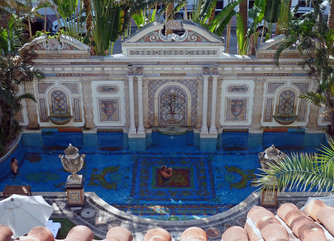 In this Tuesday, Dec. 26, 2017, photo, Joey Cargill of Manila, from the Philippines, left, and David Tamuty of Fort Lauderdale, Fla., lounge in the swimming pool lined with 24-karat gold tiles at The Villa Casa Casuarina in Miami Beach, Fla., as seen from the hotel's rooftop deck. The boutique hotel was once the home of slain fashion designer Gianni Versace. (AP Photo/Jennifer Kay)