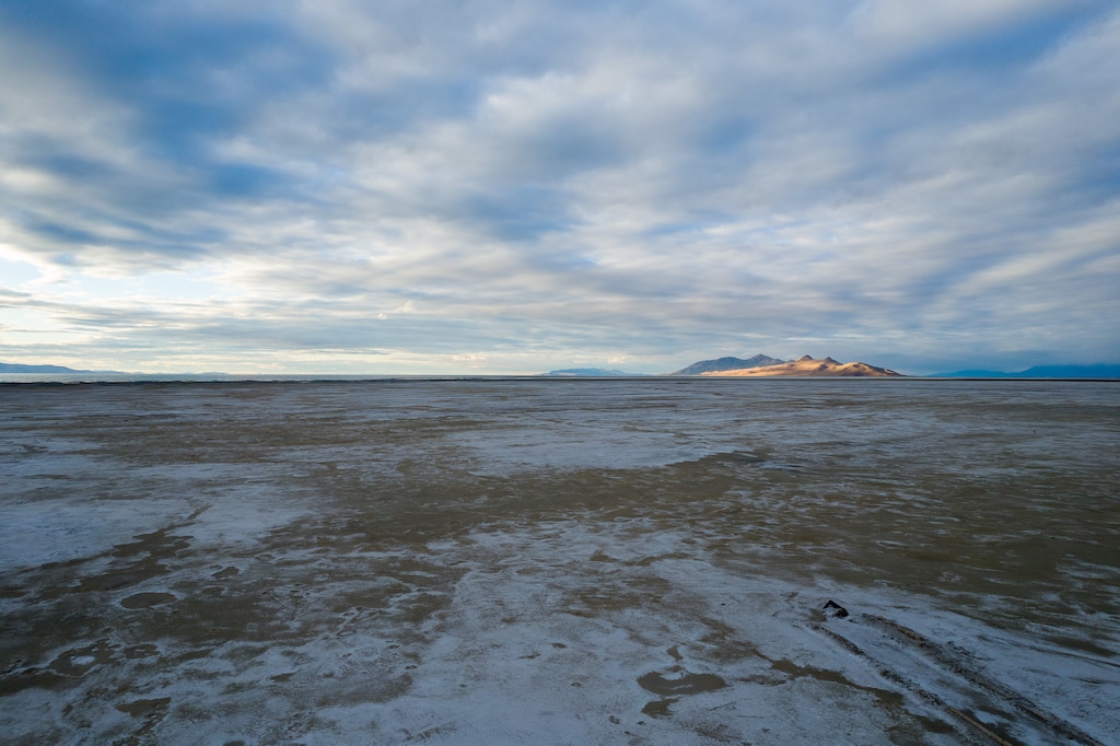 (Trent Nelson  |   The Salt Lake Tribune) The setting sun lights Antelope Island in the distance from the receding shore of the Great Salt Lake on Thursday, Oct. 14, 2021.
