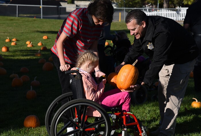 (Francisco Kjolseth  |  The Salt Lake Tribune)  Tanner Farnsworth, 18, with Latinos in Action at Jordan High School and Dan Blanchard with the Department of Corrections help a young student at Jordan Valley School in Midvale, Canyon District's school for students with severe disabilities, pick out a pumpkin from a pumpkin patch set up in front of the school on Wed. Oct. 24, 2018. Inmates who take part in the Green Thumb Nursery program at the Utah State prison grew and harvested the pumpkins that were donated to the school for the 10th year.