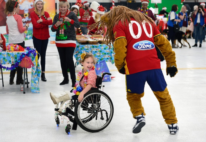 (Scott Sommerdorf   |  The Salt Lake Tribune)   Penelope Pedersen has fun with the RSL mascot "Leonardo the Lion" as patients from Primary ChildrenÕs and Shriners Hospitals were treated to a unique experience on Saturday at a Delta hangar of the Slat Lake International airport. They boarded a Boeing 737 which taxied to their final destinationÑSantaÕs Winter Wonderland, Saturday, December 2, 2017.  