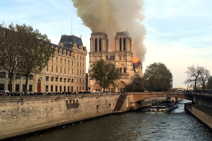 Notre Dame cathedral is burning in Paris, Monday, April 15, 2019. Massive plumes of yellow brown smoke is filling the air above Notre Dame Cathedral and ash is falling on tourists and others around the island that marks the center of Paris. (AP Photo/Lori Hinant)