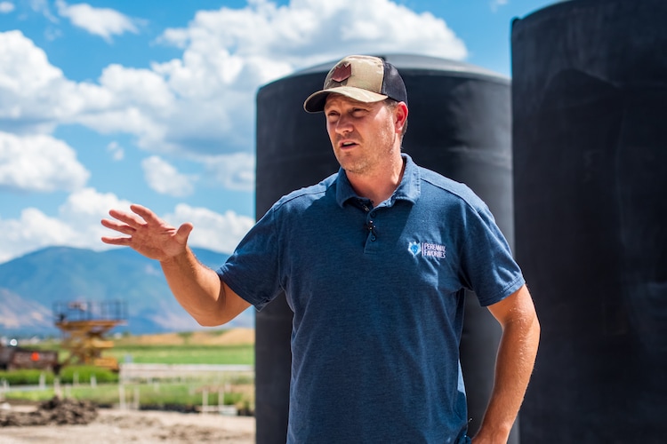 (Carter Williams | KSL.com) Cort Cox, head annual grower for Perennial Favorites, talks about the company's water reclamation system while standing in front of its three large tanks on Aug. 20. The tanks can hold up to 15,000 gallons of water at any given time.
