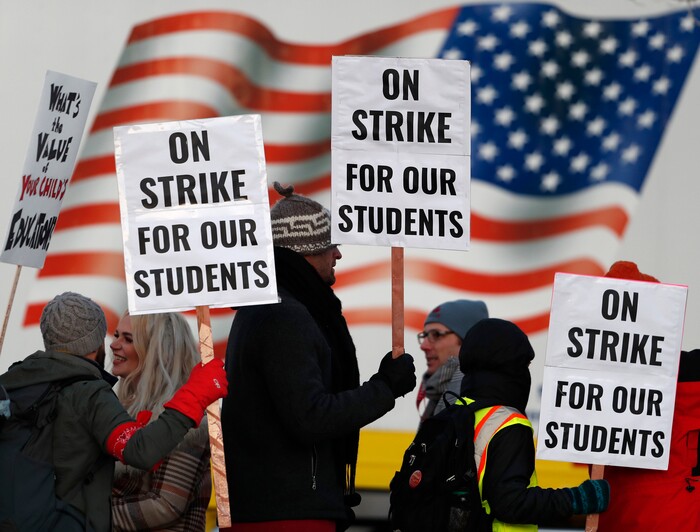 Teachers carry placards as they walk a picket line outside South High School early Monday, Feb. 11, 2019, in Denver. The strike on Monday is the first for teachers in Colorado in 25 years after failed negotiations with the school district over base pay. (AP Photo/David Zalubowski)